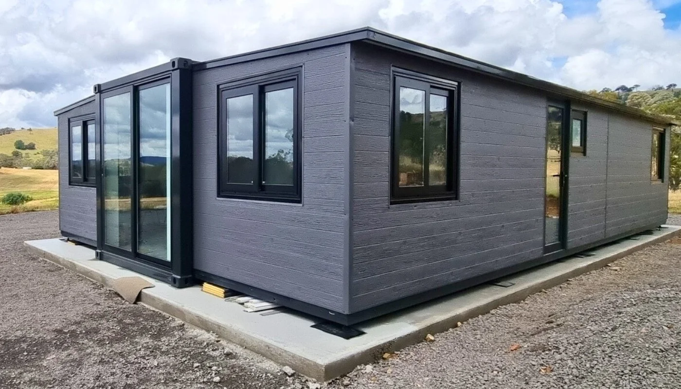 Dark-clad modular home sitting on a grass paddock in rural New Zealand
